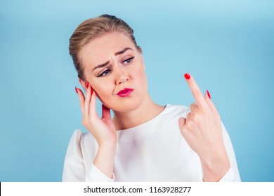 Close-up Portrait Of Nervous Unhappy Young Blonde Woman Looking At A Broken Fingernail And Crying . Red Long Nails Manicure Broken Nail Blue Background In Studio