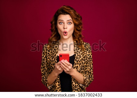 Close-up portrait of nice attractive lovely pretty charming amazed cheerful wavy-haired girl using gadget browsing media multimedia isolated over red maroon burgundy marsala color background