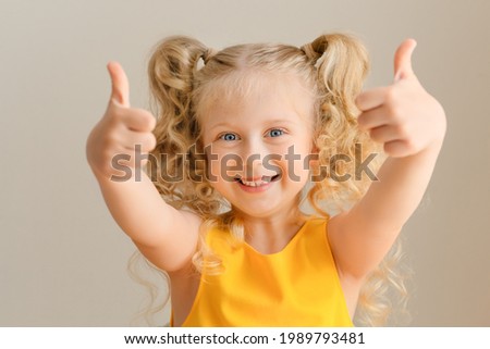 Close-up portrait of nice cute cheerful small little girl, showing double thumbs-up