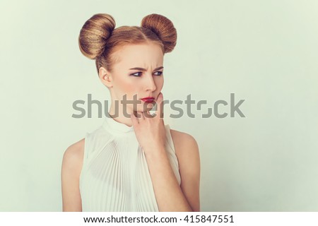 Close-up portrait of offended beautiful girl with funny hairstyle.  Sly and scheming young woman face expression.