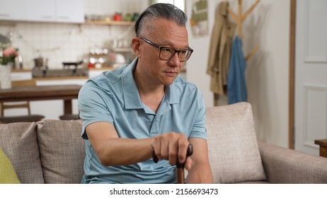 Closeup Portrait Of Old Male Asian Dementia Patient Sitting Alone With A Stick And Blank Expression On Face In The Living Room At Home