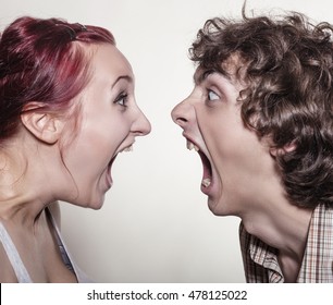 Close-up portrait of a pair of angry shouting against each other on a white background