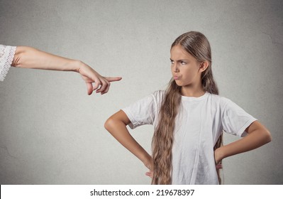 Closeup portrait parent pointing at child in white t-shirt scolding go to room grounded for misbehaving while kid is looking disobedient hands on hips, isolated grey wall background. Negative emotion - Powered by Shutterstock