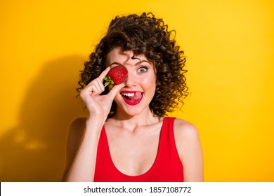 Closeup Portrait Photo Of Charming Tricky Young Girl Hand Hold Strawberry Cover Eye Stick Out Tongue Lick Lips Wear Red Singlet Unclothed Shoulders Isolated Bright Yellow Color Background