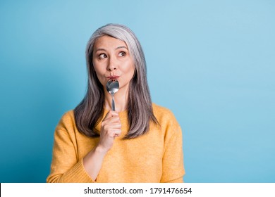 Close-up Portrait Photo Of Cute Lovely Retired Old Lady Dreamy Look Lick Spoon Thinking Imagining Eating Family Dinner Restaurant Wear Yellow Jumper Bright Blue Color Background