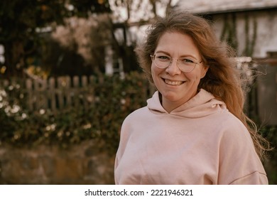 Close-up portrait photography of a young smiling woman looking straight into the camera; she is wearing a pink hoodie - Shutterstock ID 2221946321