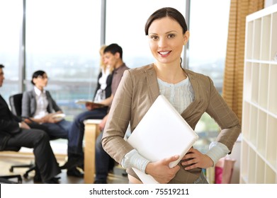 Closeup Portrait Of Pretty Cheerful Business Woman In An Office Environment Holding Laptop. Large Panoramic Window On Background