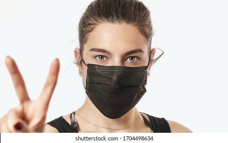 A close-up portrait of a pretty female wearing a surgical mask isolated on a white background - Shutterstock ID 1704498634