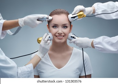 Nahaufnahme eines Porträts von ziemlich glücklicher junger Frau und Händen in Handschuhen, die medizinische Geräte halten, die ihr Gesicht berühren