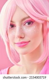 Close-up portrait of a pretty teen girl with pink hair and bright pink makeup with glitter freckles. Asian anime style. Hairstyle, cosmetics and makeup.