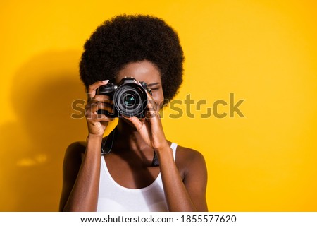 Close-up portrait of pretty wavy-haired brunette girl using digicam taking pictures snap isolated over bright yellow color background