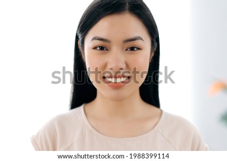 Close-up portrait of pretty woman. Beautiful young woman of Asian ethnicity with long brunette hair, looking directly at the camera, smiling friendly