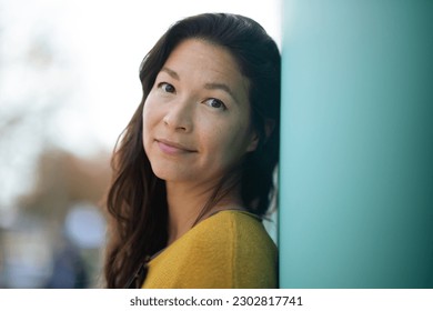 Close-up portrait of pretty young asian woman leaning to a wall outside and staring at camera - Shutterstock ID 2302817741