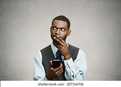 Closeup Portrait Puzzled Confused Business Man Looking Up Thinking What To Reply To Received Text Message On Cell Phone, Texting Isolated Black Background. Human Face Expression Reaction Body Language