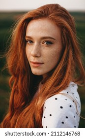 Close-up portrait of a redheaded woman with freckles looking at camera while posing outdoor. Natural beauty concept. Beautiful girl. Pretty young woman. Outdoor