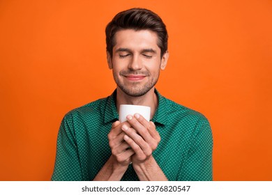 Closeup portrait of relaxing young guy enjoy his morning cacao cappuccino hold cup fresh beverage aroma isolated on orange color background - Powered by Shutterstock