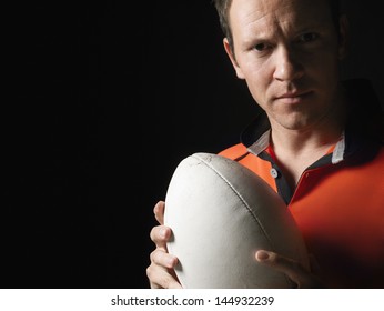 Closeup portrait of a rugby player holding ball against black background - Powered by Shutterstock