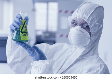 Close-up Portrait Of A Scientist In Protective Suit With Hazardous Blue Chemical In Flask At The Laboratory