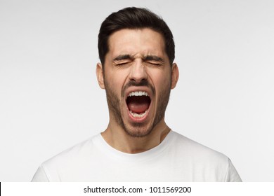 Closeup portrait of screaming with closed eyes crazy young man isolated on gray background - Shutterstock ID 1011569200