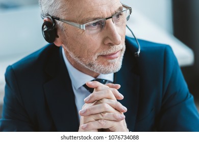 close-up portrait of senior businessman in eyeglasses and headset looking away - Powered by Shutterstock