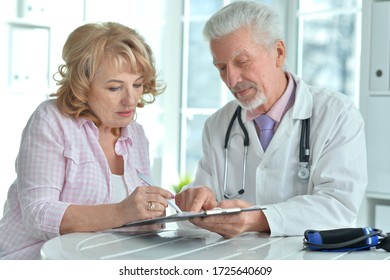 Close-up portrait of senior doctor with emotional elderly patient posing in his office