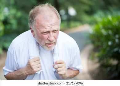 Closeup portrait, senior guy holding towel, very tired, exhausted from over exertion, sun stroke, isolated outdoors outside green trees background - Shutterstock ID 217177096
