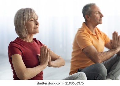 Closeup Portrait Of Senior Man And Woman In Sportswear Practicing Meditation Together Indoors, Sitting Next To Each Other In Lotus Position With Closed Eyes, Relaxation At Home, Stress Relief Concept