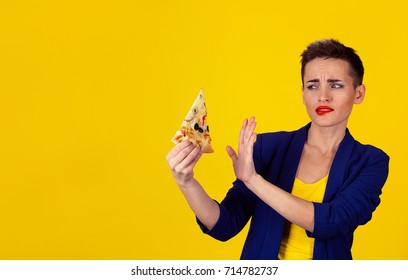 Closeup Portrait Serious Business Woman Saying No To Fatty Pizza, Trying To Withstand, Resist Temptation To Eat It Isolated Yellow Wall Background Short Hair Red Lips Blue Suit. Human Face Expression