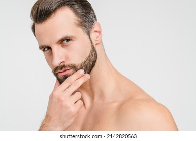 Closeup portrait of serious pensive caucasian attractive young shirtless naked man looking at camera touching his unshaven face, wants to use razor for barber shop care isolated in white background