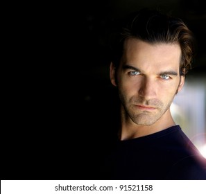 Closeup portrait of a sexy male model with lots of dark copy space