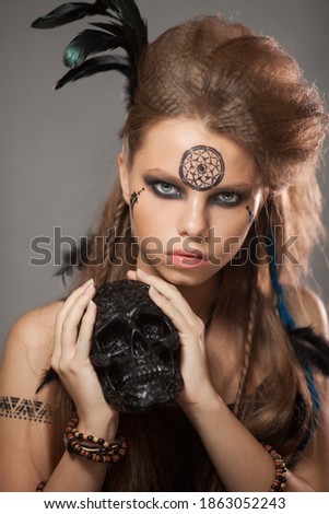 Closeup portrait of shamanic female with black human skull.