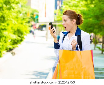 Closeup Portrait Shocked Shopper Woman Looking At Her Smart Phone, Discovered Great Online Deal, Sale, Receiving Surprising News Isolated Outside New York City Background. Emotions, Facial Expression