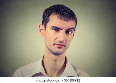 Closeup Portrait Of Skeptical Man Looking Suspicious, Some Disgust On His Face Mixed With Disapproval Isolated On Gray Background. Negative Human Emotions, Facial Expressions, Feelings