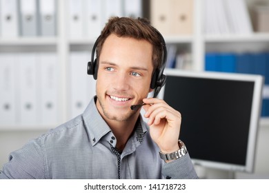 Closeup portrait of a smart smiling young man with headset in the office