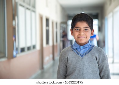 Closeup portrait of smiling 6-7 years Indian kid, standing straight at school campus in school uniform and looking at camera