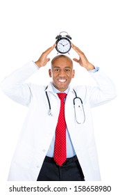 Closeup Portrait Of A Smiling, Being On Time, Happy Male Doctor Holding An Alarm Clock Above His Head, Isolated On A White Background. Health Care Reform, Medicaid Reimbursement. Patient Appointment 