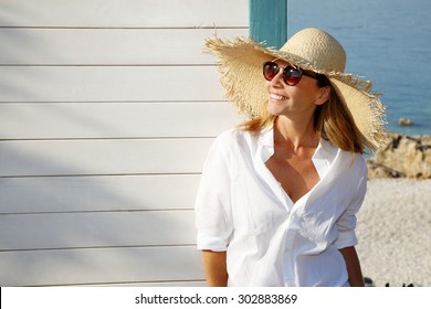 Close-up portrait of smiling female by the sea. Happy woman standing at the seaside and looking away. 