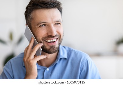 Closeup portrait of smiling handsome young businessman talking on mobile phone indoors, copy space