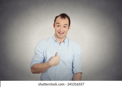 Closeup portrait smiling, happy, surprised, young business man, funny looking guy asking question, you talking to me, you mean me? Isolated grey wall background. Human emotions, facial expressions