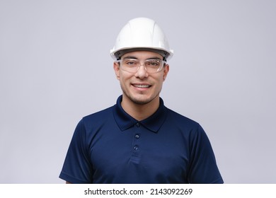 closeup portrait of smiling man architect, builder in blue T-shirt, white helmet and glasses on grey background, foreman concept - Powered by Shutterstock