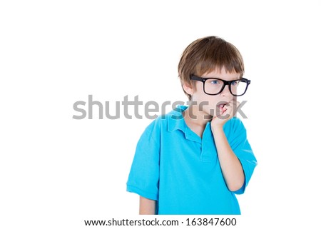 Closeup portrait of smiling smart adorable young boy in blue shirt with big black glasses thinking daydreaming about something serious chin on hand, isolated on white background, copy space to left