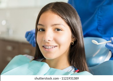 Close-up portrait of smiling teenage girl with braces against dentist standing in clinic