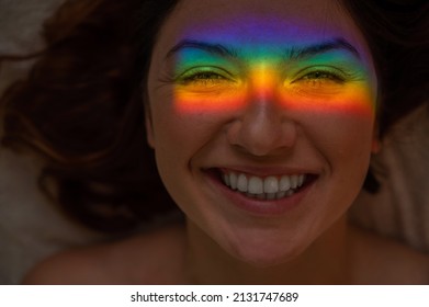 Close-up Portrait Of Smiling Woman With Ray Of Rainbow Light On Her Face. 