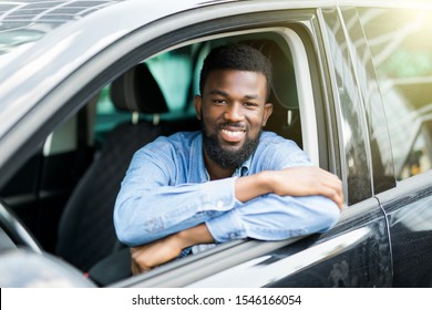 Closeup portrait smiling young man sitting in his new car excited ready for trip