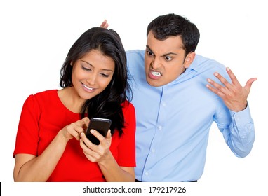 Closeup Portrait Of Sneaky Jealous Possessive Boyfriend Watching Girlfriend Happily Texting Someone Else, Isolated On White Background. Negative Emotion Facial Expression Feelings Conflict Concept