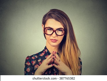 Closeup portrait sneaky, sly, scheming young woman in glasses plotting something isolated on gray background. Negative human emotions, facial expressions, feelings, attitude, reaction 