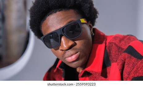 Close-up portrait of a stylish black man with sunglasses and red plaid shirt. Fashionable and confident, with a focus on details and texture. - Powered by Shutterstock