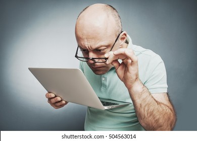 Closeup portrait surprised man working on laptop computer looking carefully at screen. on gray background