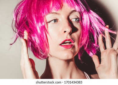 Close-up portrait of surprised young sexy woman in pink bob cut wig, bright rose lips makeup. Vibrant color. People naturally look skin freckles. Gossip girl. Surprising news. Curiosity concept.