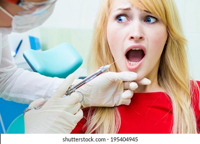 Closeup portrait terrified girl woman scared of needles, syringes, dentist visit siting in chair, opened mouth doesn't want dental procedure drilling tooth extraction isolated clinic office background - Powered by Shutterstock